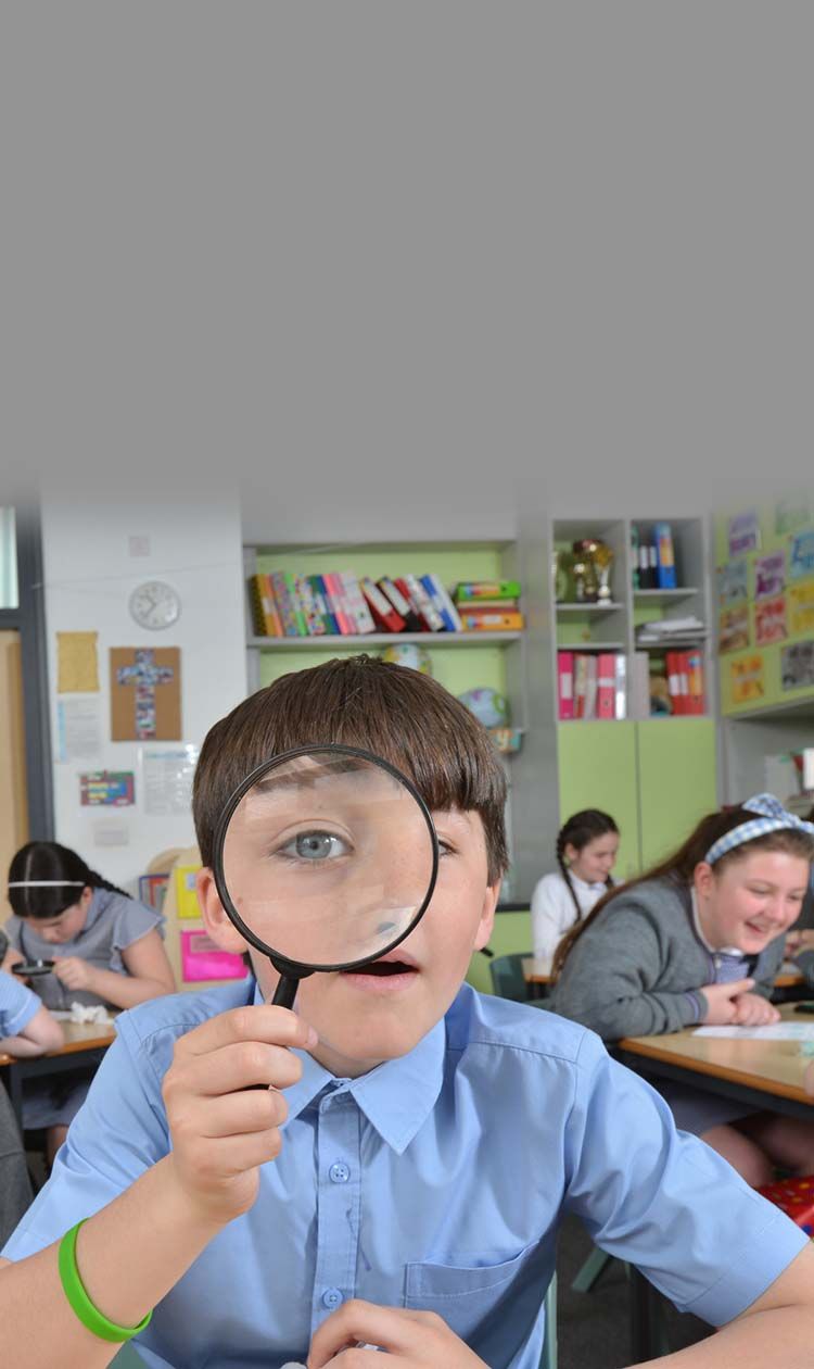 Boy in classroom looking through a magnifying glass